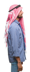 Young handsome arabian business man wearing keffiyeh over isolated background looking to side, relax profile pose with natural face with confident smile.