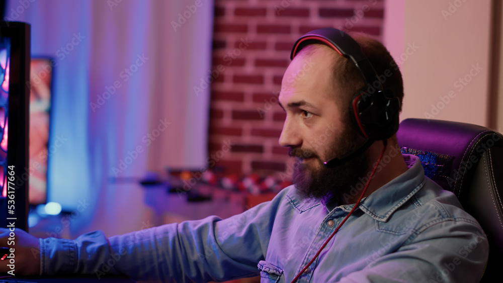 Poster closeup of man with gaming headset playing multiplayer online action game using professional pc setu