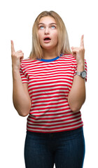 Young caucasian woman over isolated background amazed and surprised looking up and pointing with fingers and raised arms.