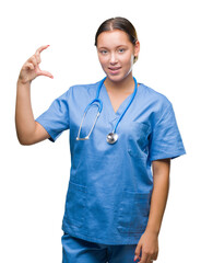 Young caucasian doctor woman wearing medical uniform over isolated background smiling and confident gesturing with hand doing size sign with fingers while looking and the camera. Measure concept.