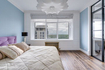 Large bright room with blue walls and a huge white chandelier and glass wall