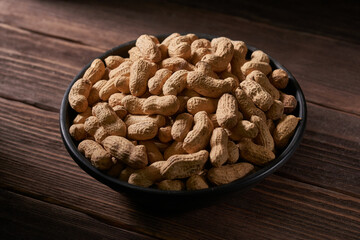 Dried peanuts in a bowl on a wooden table.