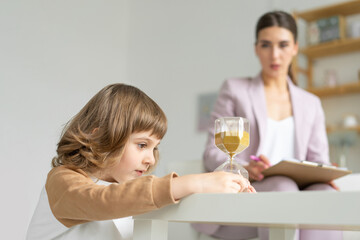 Consultations with a child psychologist. The boy is playing with an hourglass. Copy space