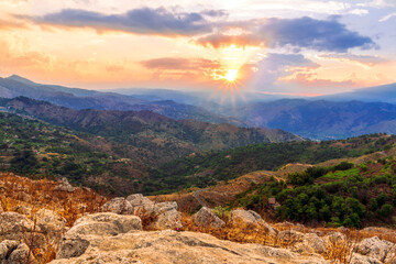 Fototapeta premium beautiful highland landscape with amazing view from a top with golden grass and green bushes to a canyon with majectic mountains and scenic cloudy sunset on background