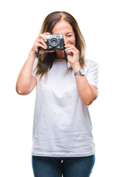 Middle age hispanic woman taking pictures using vintage photo camera over isolated background with a happy face standing and smiling with a confident smile showing teeth