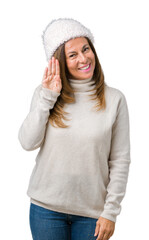 Beautiful middle age woman wearing winter sweater and hat over isolated background Waiving saying hello happy and smiling, friendly welcome gesture