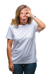 Fototapeta premium Middle age senior hispanic woman over isolated background doing ok gesture shocked with surprised face, eye looking through fingers. Unbelieving expression.