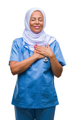 Middle age senior arab nurse woman wearing hijab over isolated background smiling with hands on...
