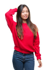 Young asian woman wearing winter sweater over isolated background confuse and wonder about question. Uncertain with doubt, thinking with hand on head. Pensive concept.