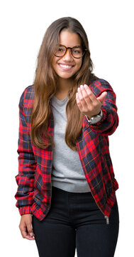 Young beautiful brunette woman wearing jacket and glasses over isolated background Beckoning come here gesture with hand inviting happy and smiling