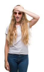 Blonde teenager woman wearing sunglasses stressed with hand on head, shocked with shame and surprise face, angry and frustrated. Fear and upset for mistake.