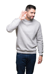 Young handsome man wearing sweatshirt over isolated background smiling with hand over ear listening an hearing to rumor or gossip. Deafness concept.