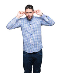 Fototapeta premium Young handsome man over isolated background Smiling pulling ears with fingers, funny gesture. Audition problem
