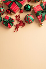 Christmas Day concept. Top view vertical photo of big present boxes with ribbon bows green gold red baubles balls and reindeer ornament on isolated beige background with empty space