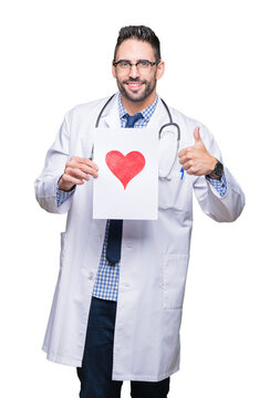 Handsome young doctor man holding paper with red heart over isolated background happy with big smile doing ok sign, thumb up with fingers, excellent sign