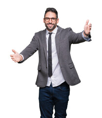Young handsome business man over isolated background looking at the camera smiling with open arms for hug. Cheerful expression embracing happiness.