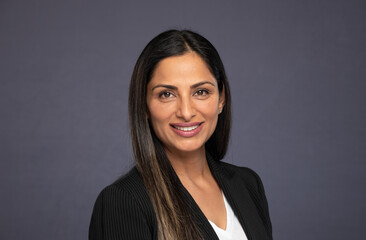 Studio headshots of beautiful Asian Indian woman in business attire on gray background. 