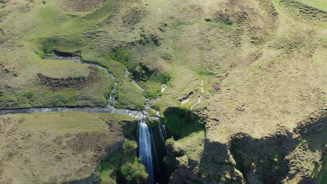 Drone Over Green Landscape Surrounding Gljufrabui Waterfall