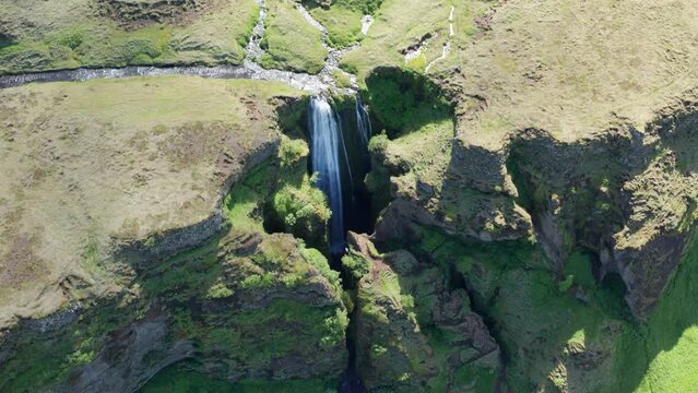 Drone Over Green Landscape Surrounding Gljufrabui Waterfall