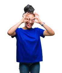 Naklejka premium Young braided hair african american girl wearing glasses over isolated background doing ok gesture like binoculars sticking tongue out, eyes looking through fingers. Crazy expression.