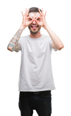Fototapeta premium Young tattooed adult man doing ok gesture like binoculars sticking tongue out, eyes looking through fingers. Crazy expression.