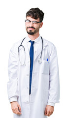 Fototapeta premium Young doctor man wearing hospital coat over isolated background winking looking at the camera with sexy expression, cheerful and happy face.