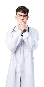 Young doctor man wearing hospital coat over isolated background shocked covering mouth with hands for mistake. Secret concept.
