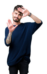 Fototapeta premium Young handsome man over isolated background Smiling doing frame using hands palms and fingers, camera perspective