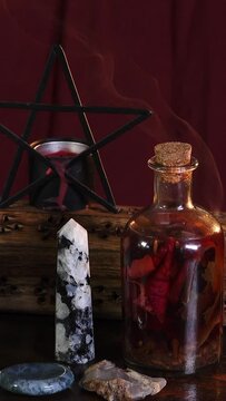 Vertical video of Wiccan altar with potion, pentagram, crystals, incense is burning with smoke curling beautifully 