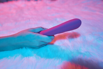 desire concept : Woman lying in bed holding a dildo vibrator in her hand to help herself.