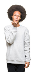 Young african american man with afro hair wearing sporty sweatshirt looking at the camera blowing a kiss with hand on air being lovely and sexy. Love expression.