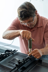 Mexican Latino man repairing a TV screen, checking for faults.