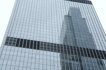 Modern skyscraper with glass windows. From below of contemporary tall building with reflection of skyscraper.