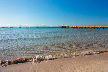 Mallorca. Playa de Alcudia. Orilla de la playa con aguas transparentes y un puente de madera o...