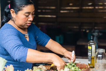 Portrait of a Latina woman preparing salad in a traditional kitchen. Copy space.