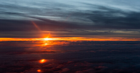 Fototapeta na wymiar Atardecer anaranjado con nubes desde los cielos