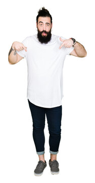Young hipster man with long hair and beard wearing casual white t-shirt Pointing down with fingers showing advertisement, surprised face and open mouth