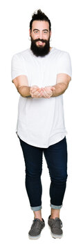 Young hipster man with long hair and beard wearing casual white t-shirt Smiling with hands palms together receiving or giving gesture. Hold and protection