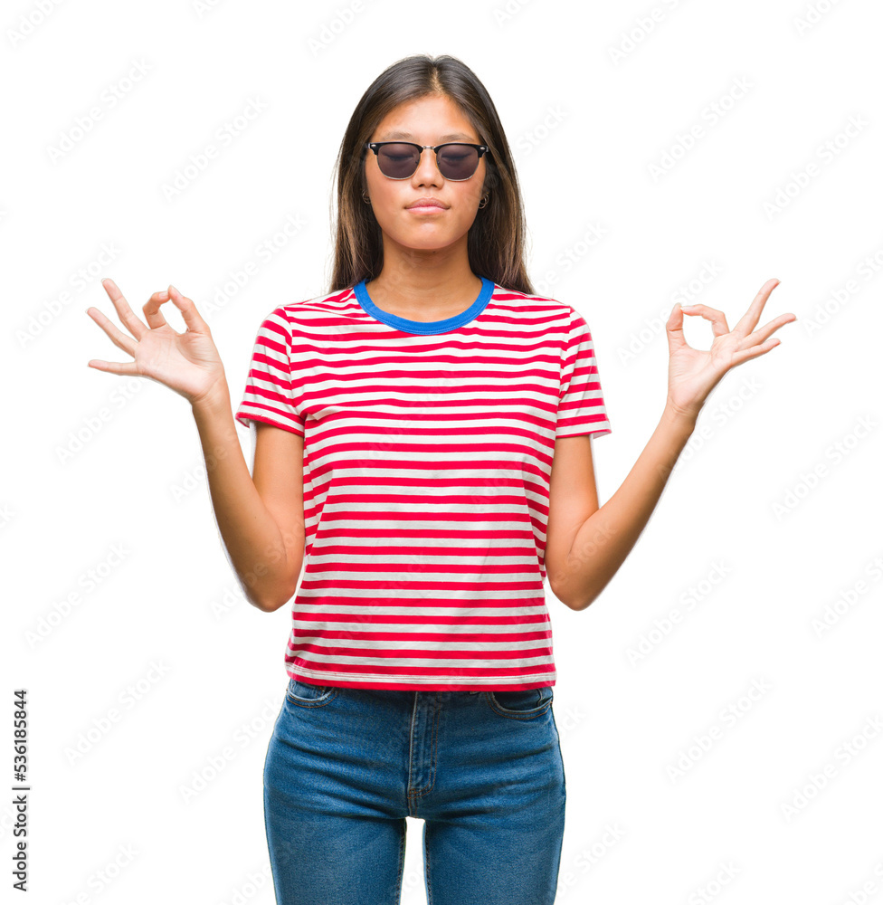 Poster Young asian woman wearing sunglasses over isolated background relax and smiling with eyes closed doing meditation gesture with fingers. Yoga concept.