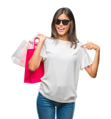 Young asian woman holding shopping bags on sales over isolated background with surprise face...