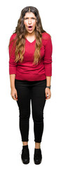 Obraz premium Young beautiful woman wearing red sweater afraid and shocked with surprise expression, fear and excited face.