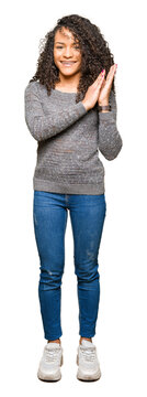 Young beautiful woman with curly hair wearing grey sweater Clapping and applauding happy and joyful, smiling proud hands together