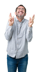 Fototapeta premium Handsome middle age elegant senior man wearing glasses over isolated background smiling crossing fingers with hope and eyes closed. Luck and superstitious concept.