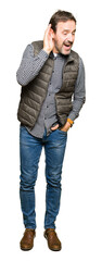 Fototapeta premium Middle age handsome man wearing winter vest smiling with hand over ear listening an hearing to rumor or gossip. Deafness concept.