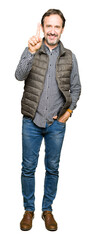 Middle age handsome man wearing winter vest showing and pointing up with finger number one while smiling confident and happy.