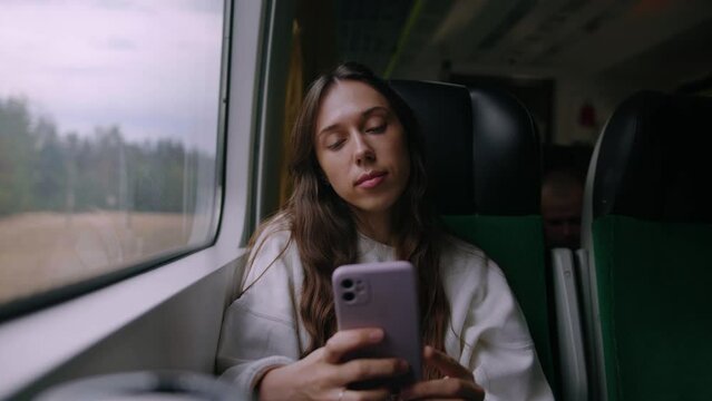 A young woman with a mobile phone during a trip on a modern train
