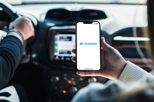 Girl inside car holding smartphone with OnlyFans app on screen. Rio de Janeiro, RJ, Brazil. October 2022