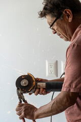 man using angle grinder, cutting a screw, friction sparks, clamping screw with tweezers...