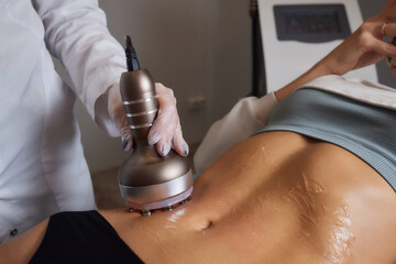 procedure removing cellulite on female abdomen, cavitation belly massage. Ultrasonic massage for...