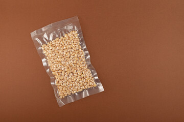Cedar nuts in transparent vacuum package. Brown background, copy space. Peeled Pine nuts